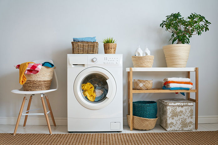 Mały kącik na pranie - wystarczy pralka, półka i krzesło oraz kosze na pranie i dekoracyjna roślina